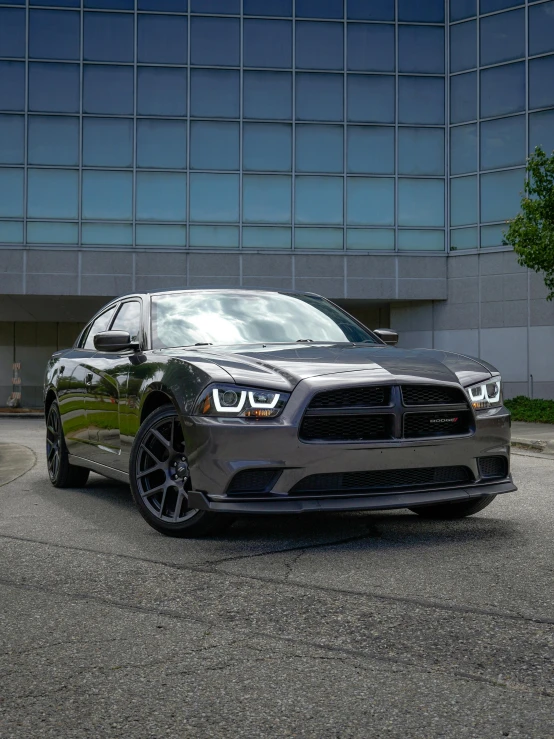 a grey dodge charge parked in front of a tall building