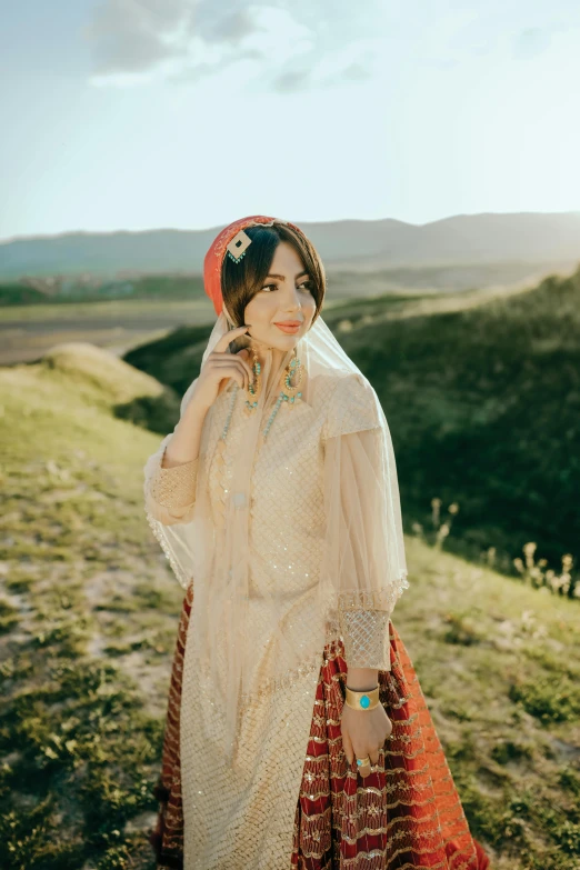 a woman in a long dress standing on a grass covered hill