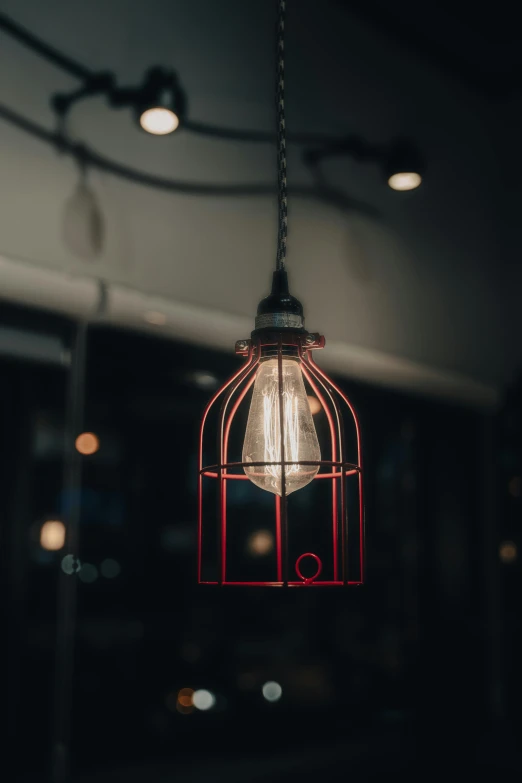 the hanging light bulb is attached to a caged fixture