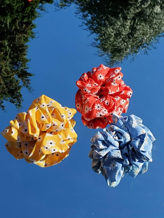 three cloth flower scrunffs hang up in the air