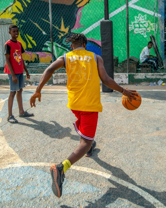 a man in a yellow shirt plays basketball with another person