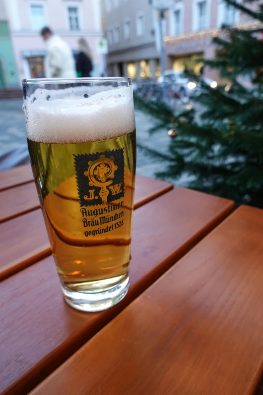 a beer sitting on top of a wooden table next to a small evergreen tree