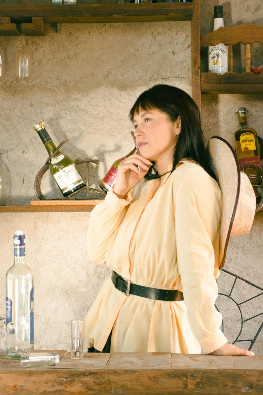 a woman standing behind a table with a bottle of wine