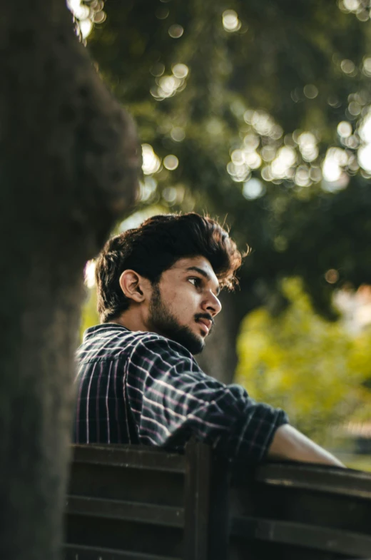 a man sits on a park bench near trees