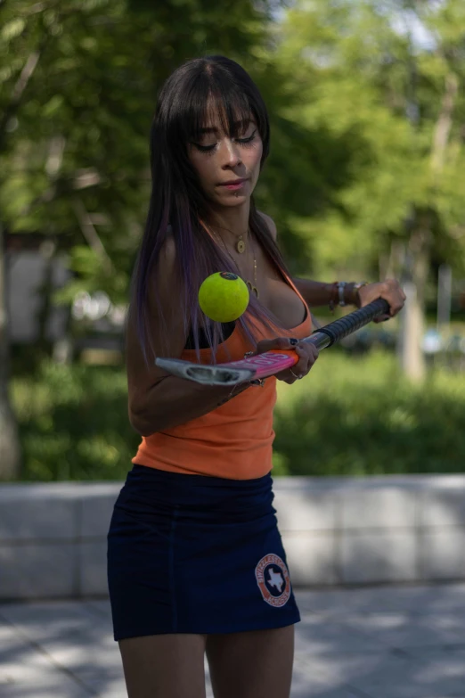 a woman in an orange tank top holding a tennis racket