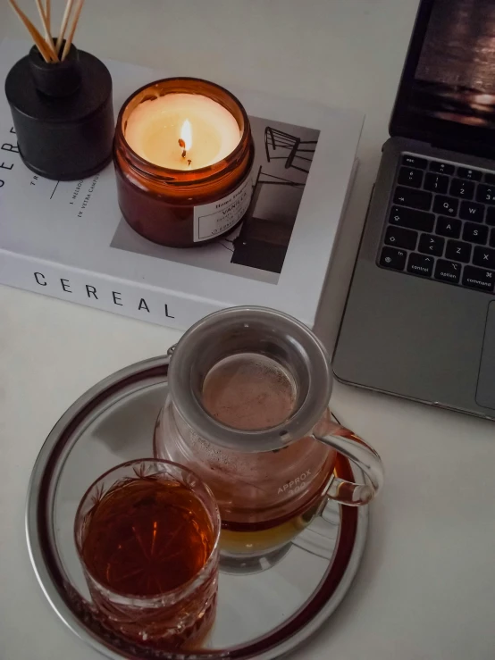 a cup filled with tea next to a laptop