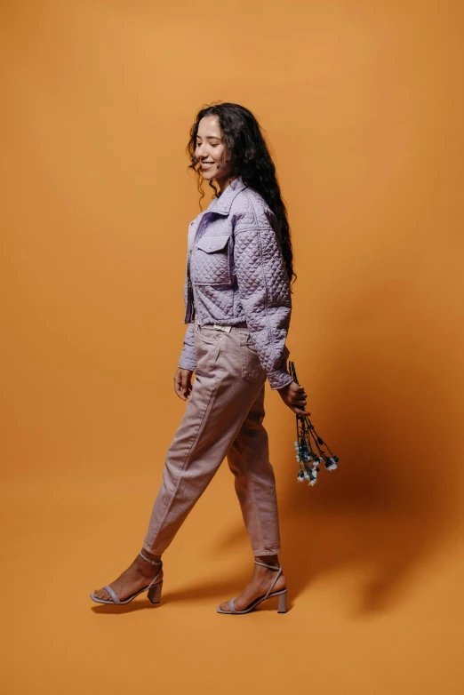 a young woman standing on an orange background with her hand on her hips