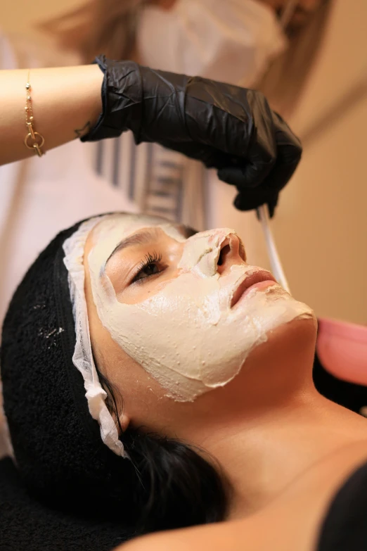 a woman getting facial care from a professional facial mask