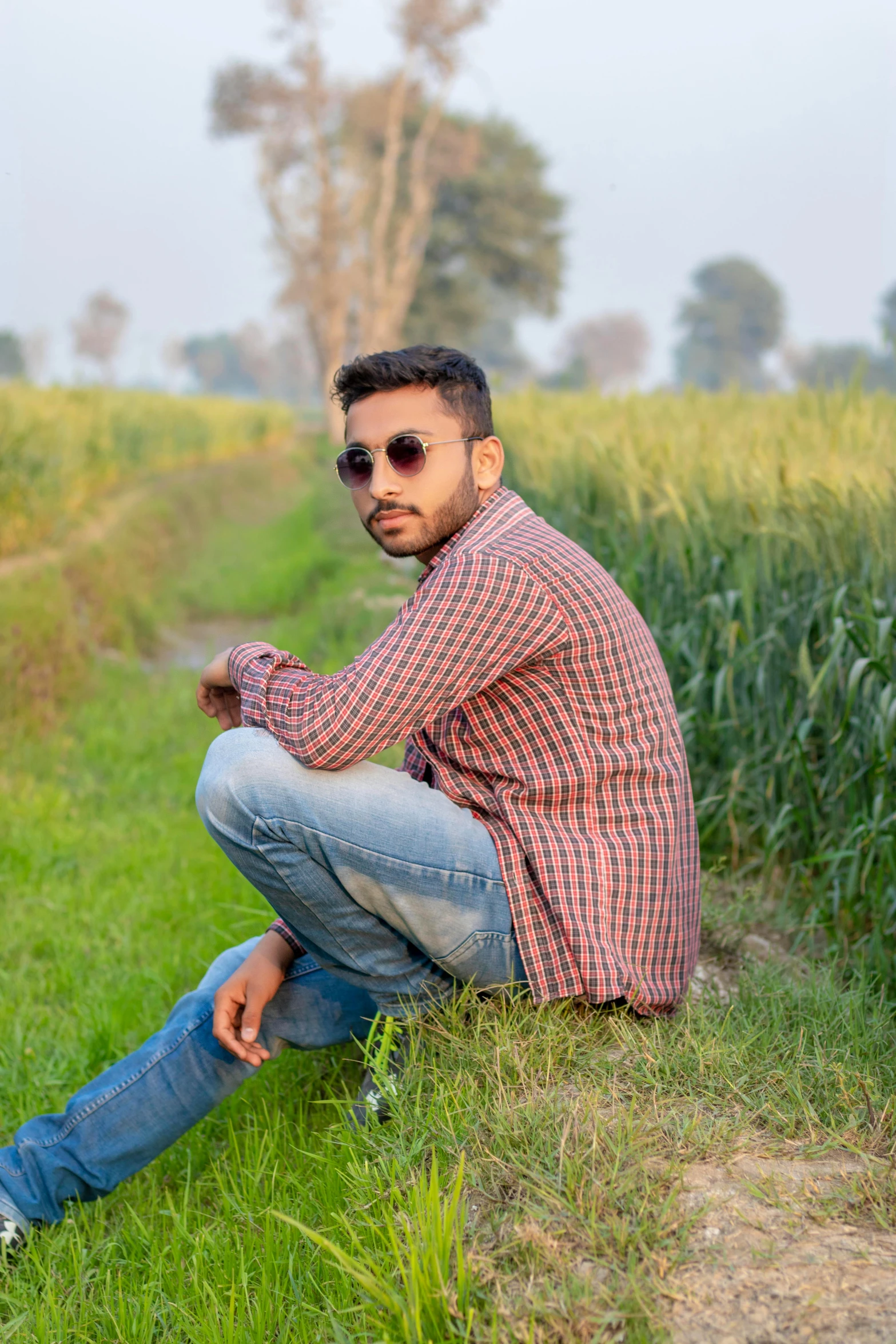 a man sitting in the grass wearing sunglasses