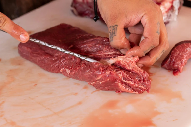 a person slicing up a piece of meat on a  board