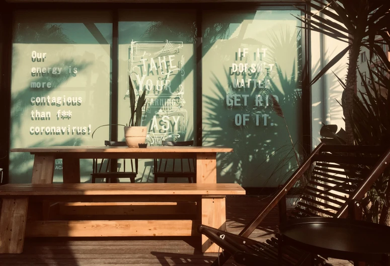 two tables, two chairs and two vases with plants behind glass