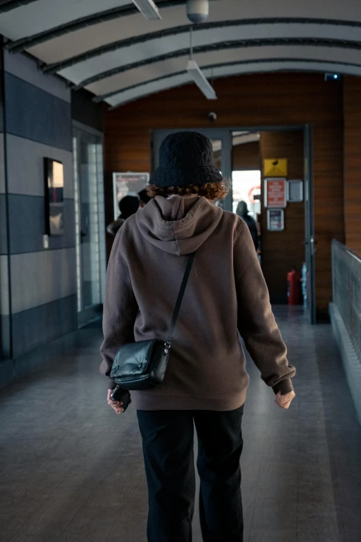 a woman is walking along a hallway carrying a small handbag