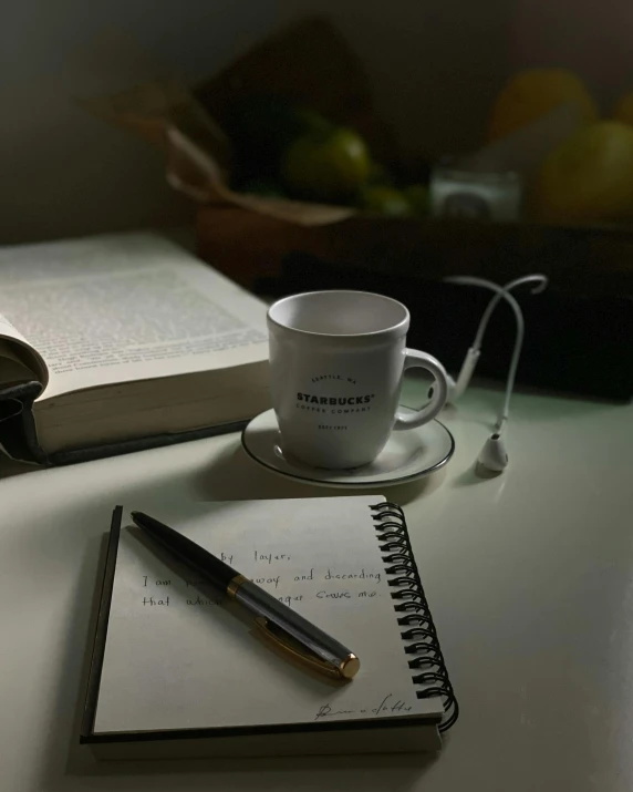 a book, pen, and cup are sitting on a desk