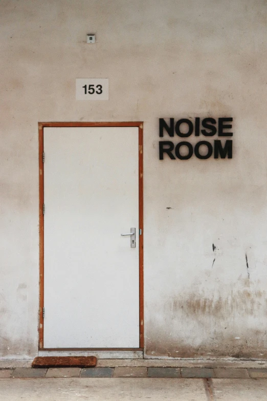 the front door of a large white door with a sign above it that says noise room