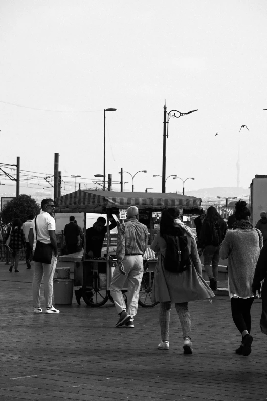 group of people walking down the road by a bus stop