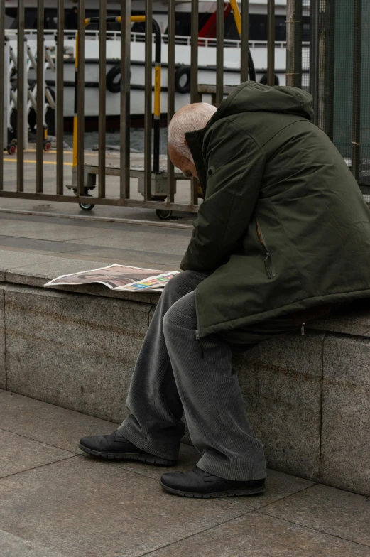 an old man sits alone outside on a street