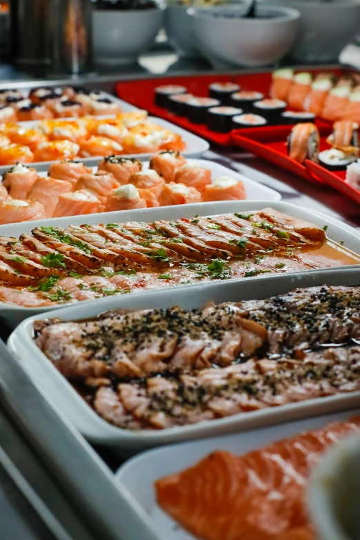 many trays of food are displayed on a buffet