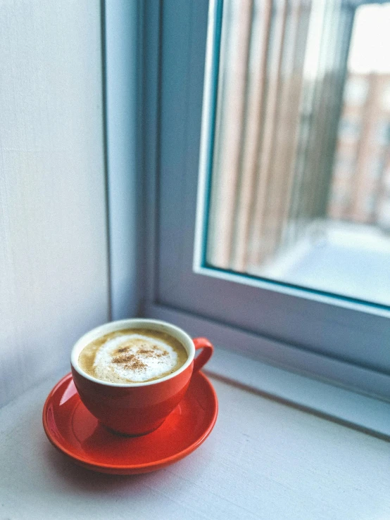 a cappuccino sitting on top of a red saucer