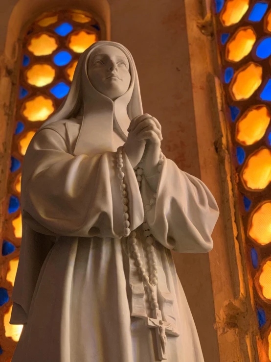 statue of nun with stained glass window in background