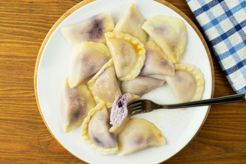 a plate of ravioli with cheese and purple flowers