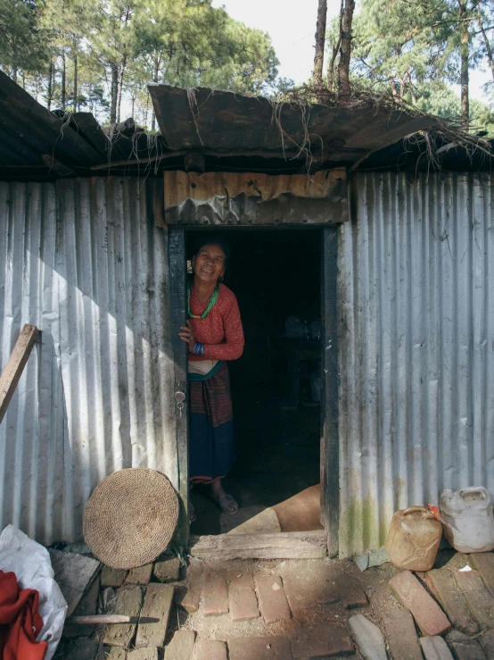 a woman stands outside of a metal structure holding a small basket