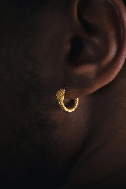 a person wearing gold ear hoop earrings