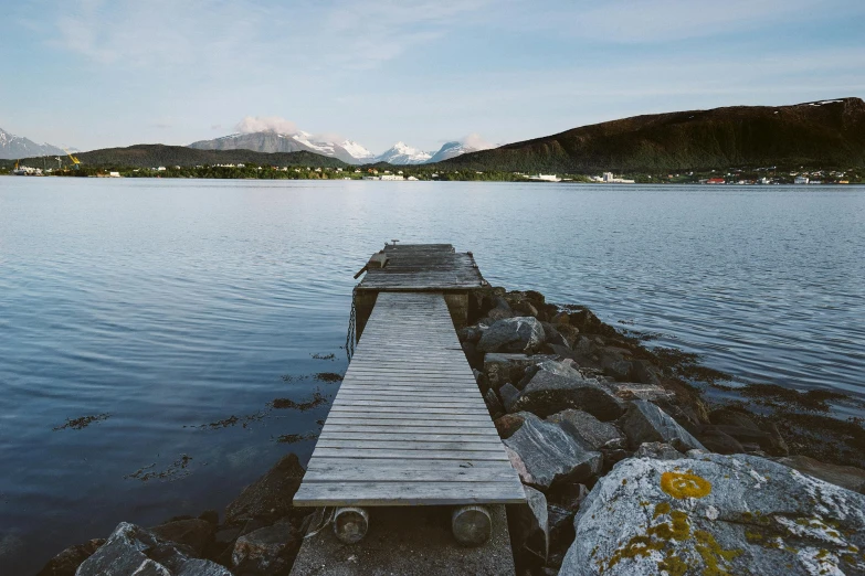 a dock on a rocky shore with the water still calm