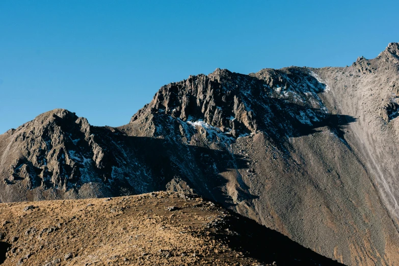 a big tall mountains near the sky with a blue sky in the background