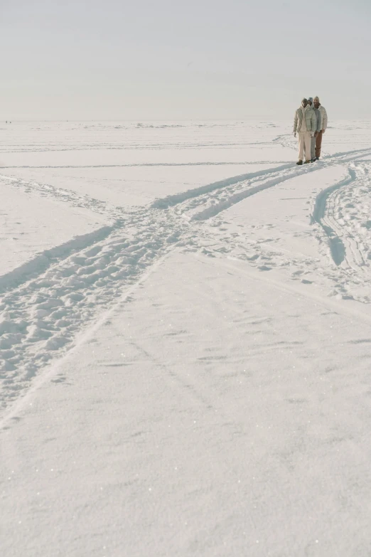 two people walking across a snow covered field