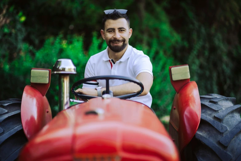 a man sitting on a red tractor while smiling