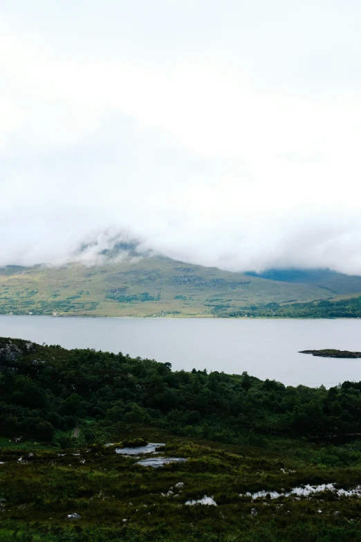 a bench is facing a lake near mountains