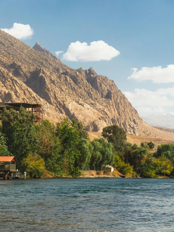 a boat floating down a river in front of tall mountains