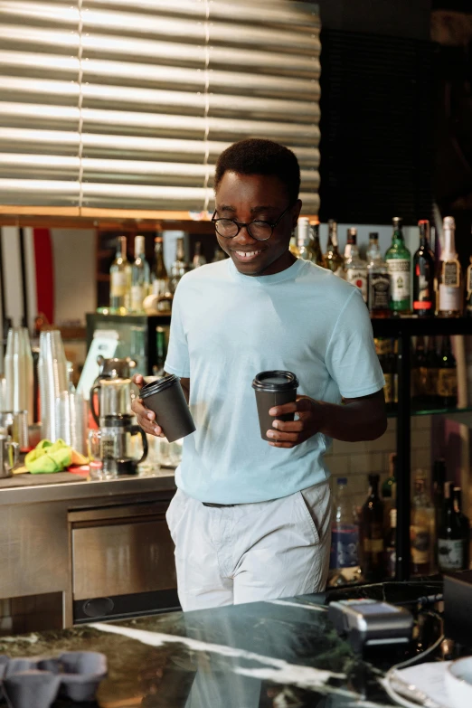 a smiling man holding a glass near a bar