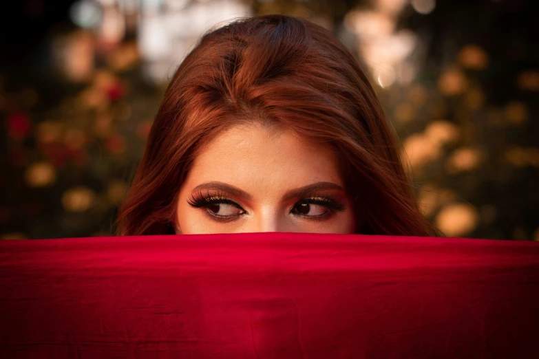 the woman with eyeliners on is hiding under a blanket