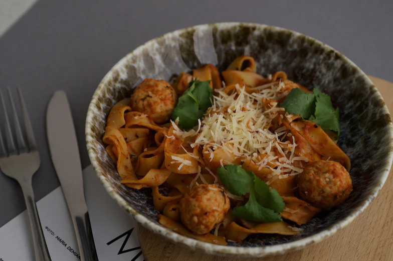 pasta and meatballs with basil are served in a bowl