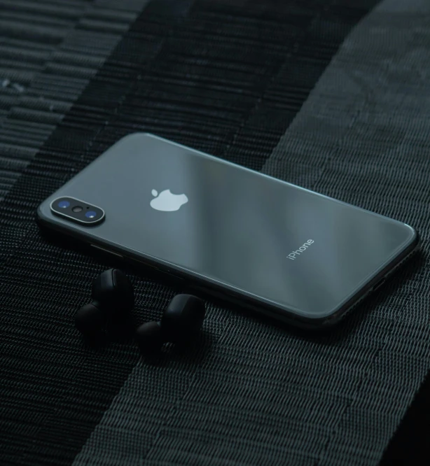 an iphone laying on top of a table with ear buds