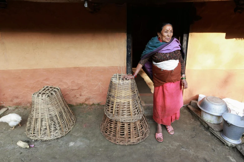 a woman stands in her doorway next to baskets and pots