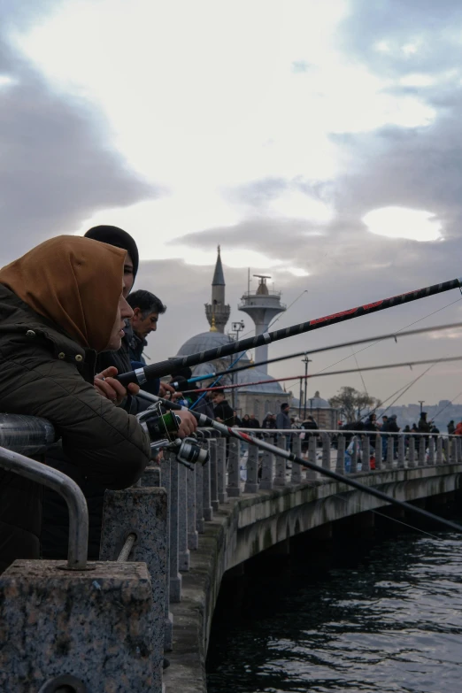 three men sitting on a fence next to a pier