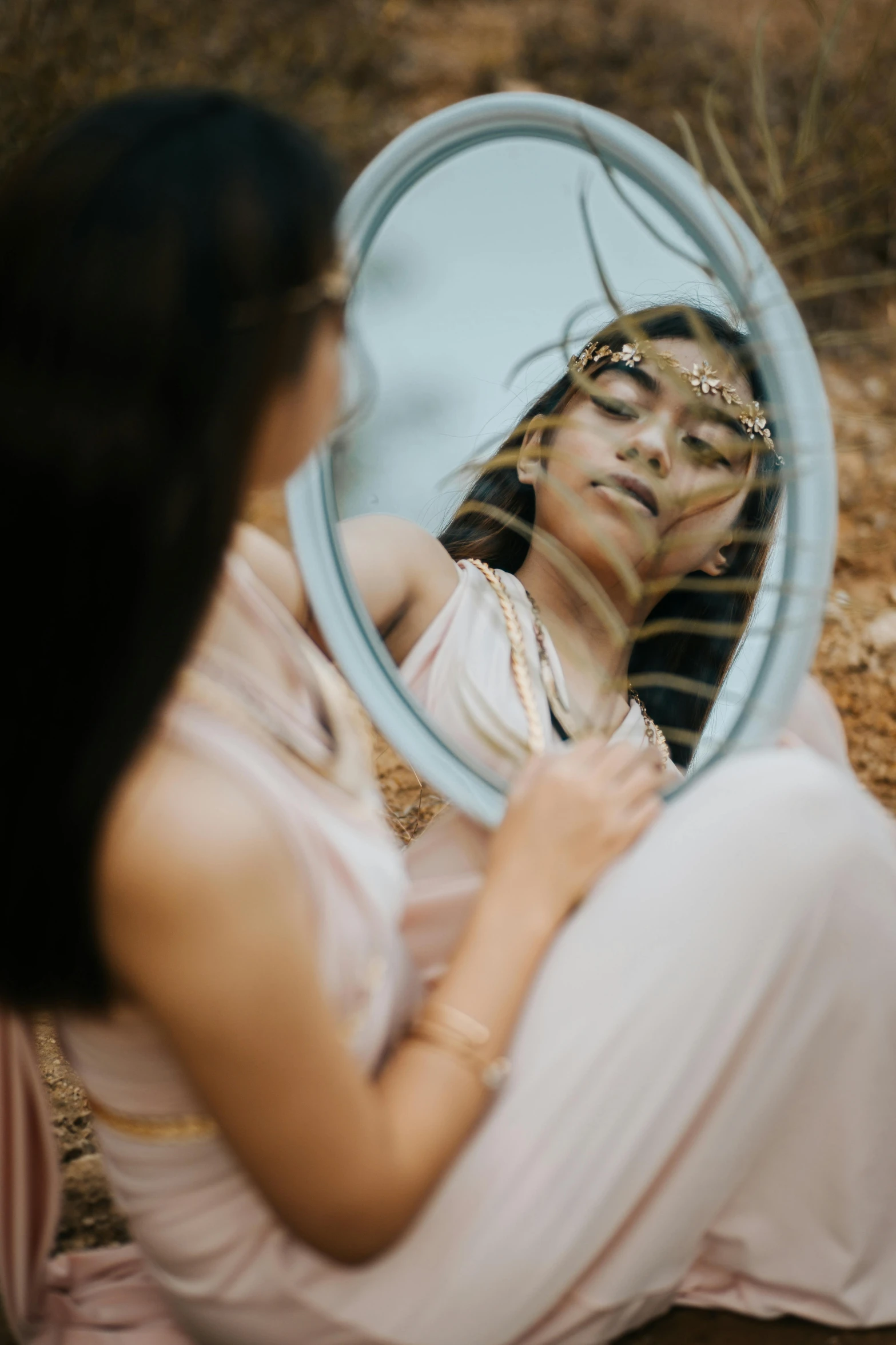 a woman sitting on the ground looking in a mirror