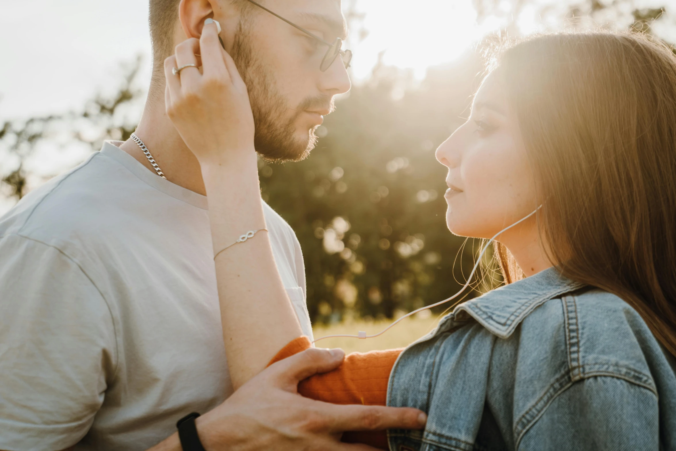 a man with earphones talks on the phone as a girl holds her hands