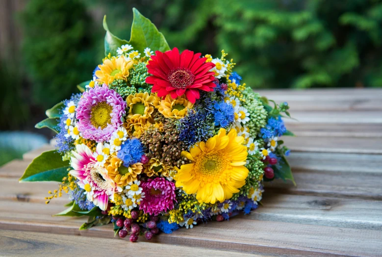 brightly colored flowers are piled on top of a wooden table