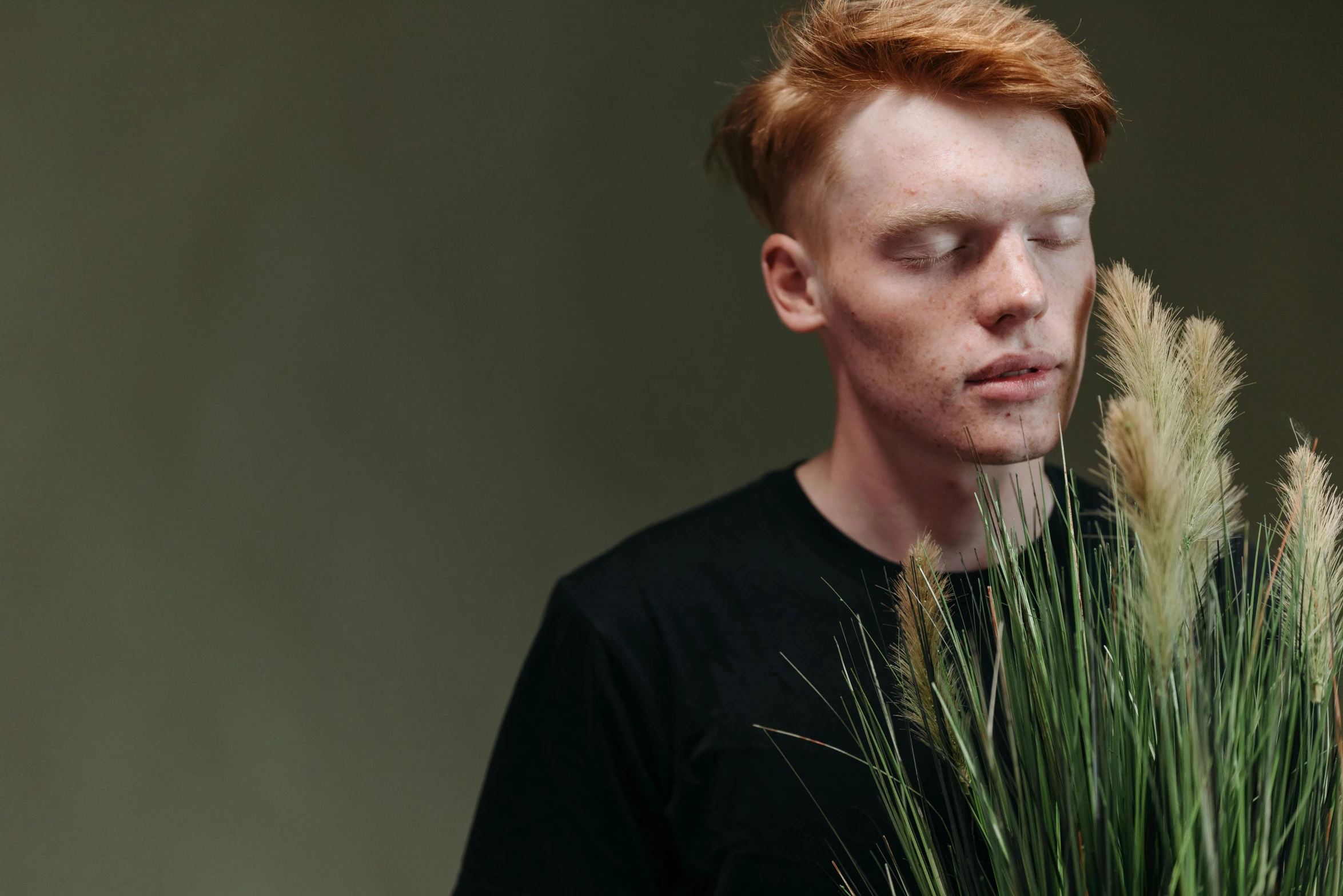 a man holding a bouquet of tall grass