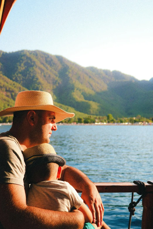 a man and child look at a lake with mountains in the background