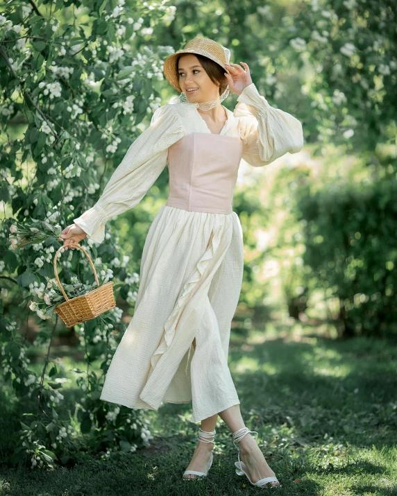 a woman wearing a vintage white dress and matching hat, holding a basket with her right hand