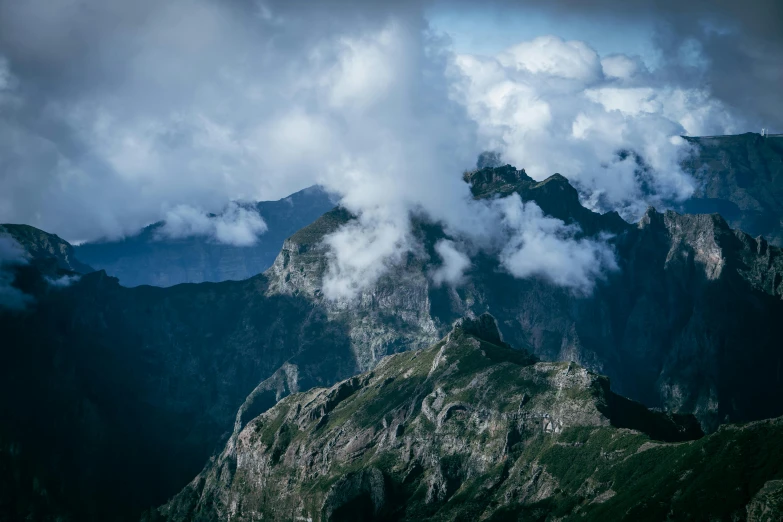 a bunch of very tall mountains under a cloudy sky