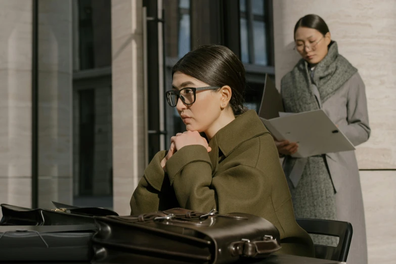 two ladies are sitting and one is reading a piece of paper