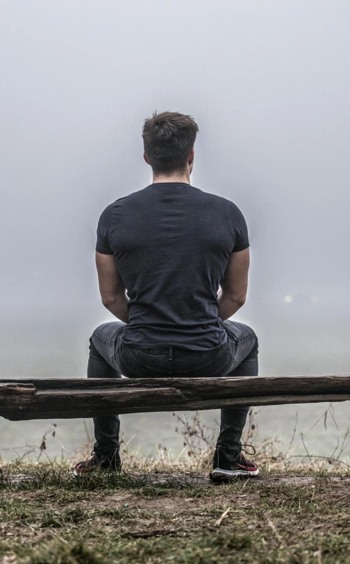 the man sitting on the bench looks out to sea