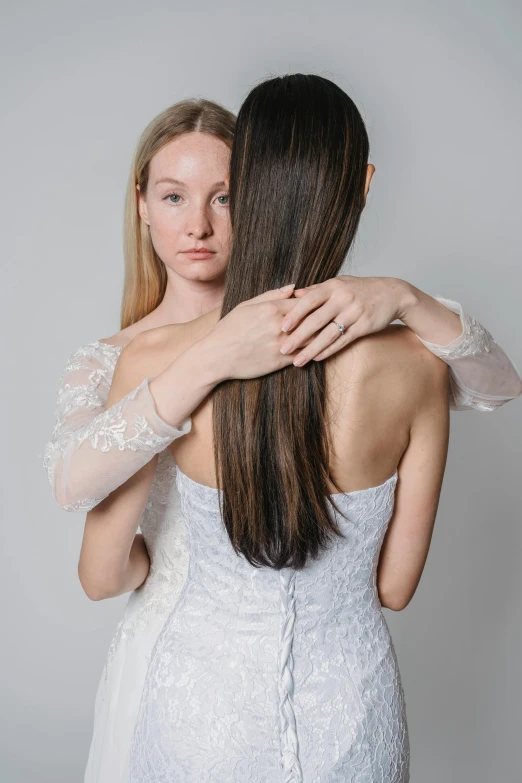 two young women are emcing each other while one is dressed in white