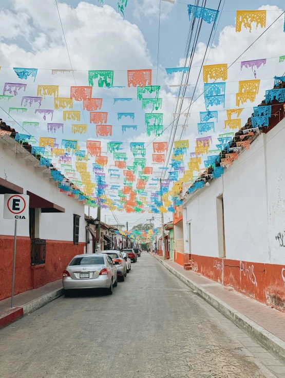 cars parked on the street under colorful paper decorations