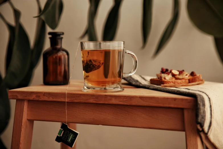 glass cup sitting on wooden table with teabag